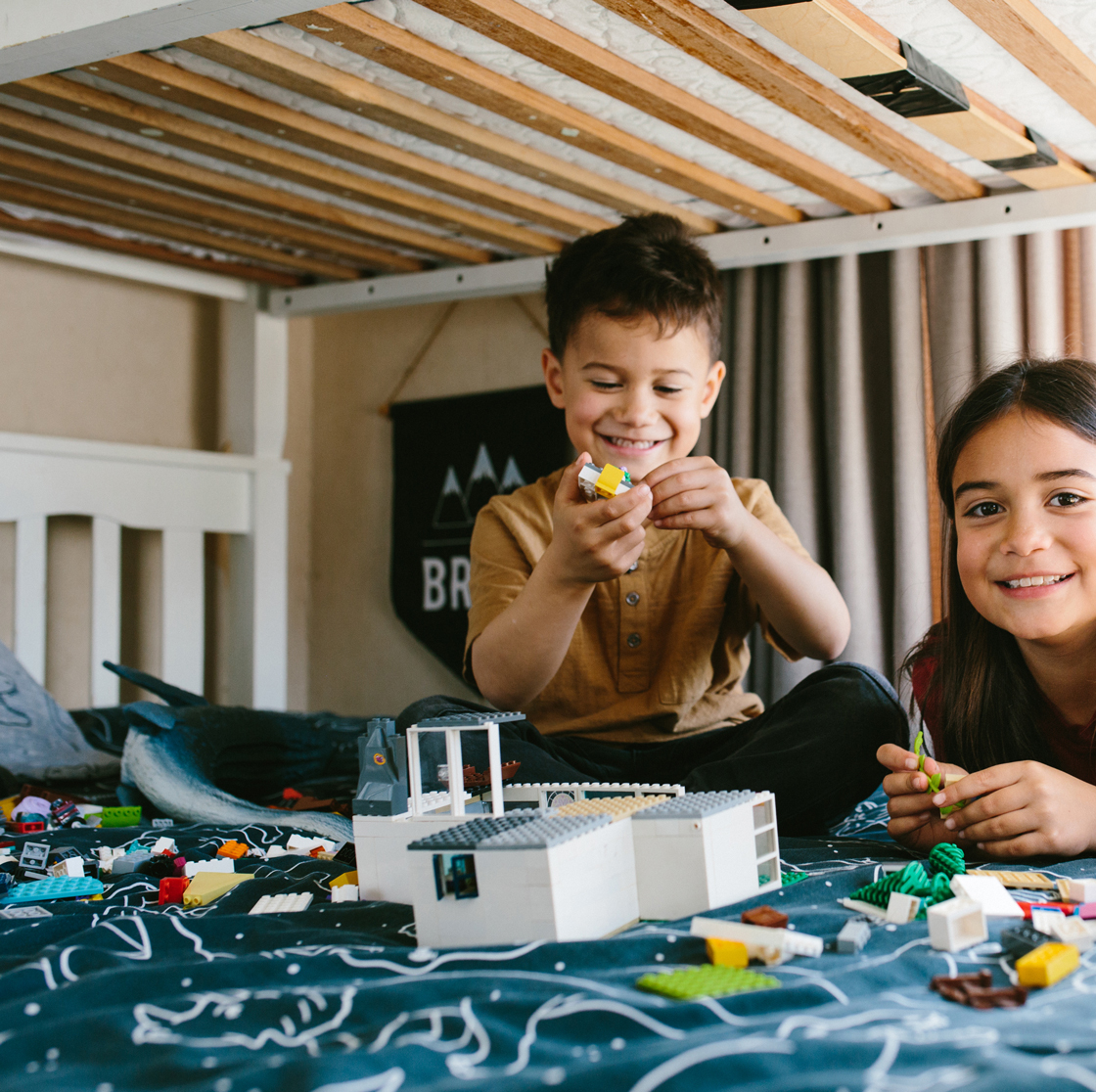 Home Capital Partners – two children on a bed building a toy house with blocks under a bunk bed.